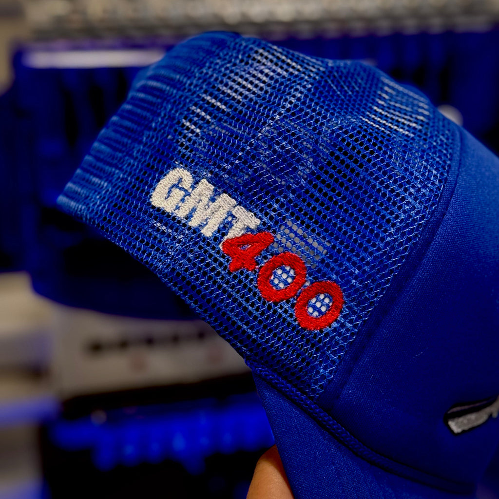 the right side of a blue trucker hat with a embroidered logo representing GMT400